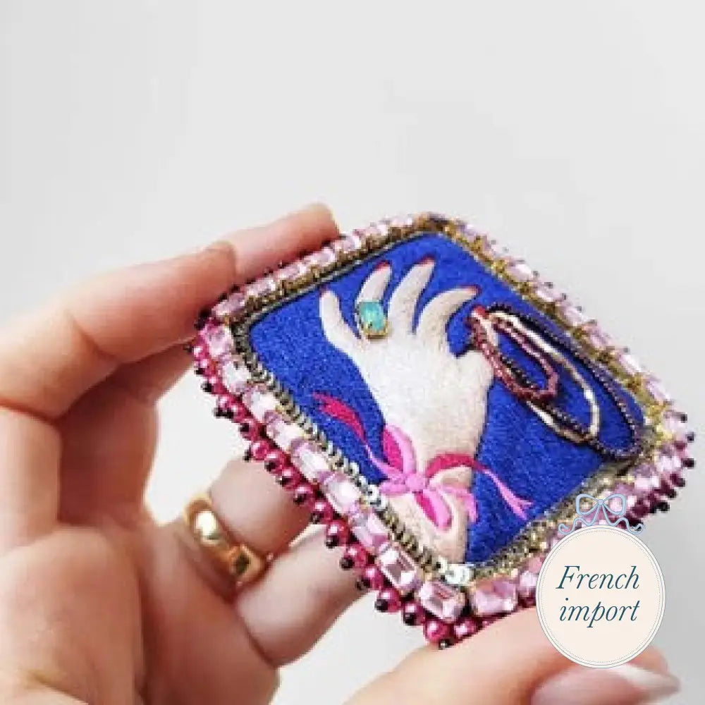 Hand Brooch Holding A Necklace Blue Background Jewelry - Brooches